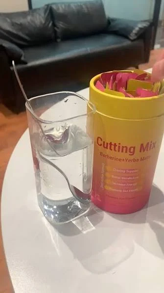 A Cutting Mix canister full of sticks next to a glass of water on a table