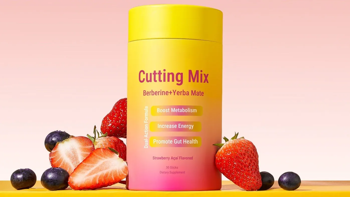The Cutting Mix canister on a yellow table against a pink background, surrounded by fresh strawberries and blueberries.